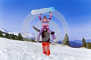 Happy snowboarder with woman on his shoulders