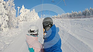 Happy snowboarders couple going up with an anchor ski lift in ski resort. They are enjoying sunny day. Winter vacation
