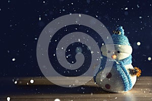 Happy snowman standing in dark winter christmas snow background. Merry christmas and happy new year greeting card with copy-space.