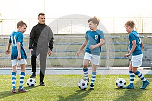 Happy soccer kids smiling on training. Group of school boys practicing soccer with a young coach