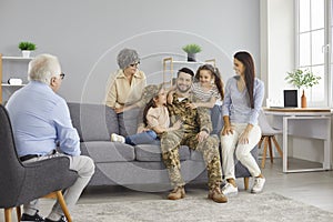 Happy soldier who& x27;s back home from military service sitting on sofa with his family