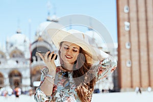 Happy solo tourist woman in floral dress talking on phone