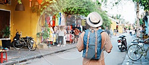 Happy Solo traveler sightseeing at Hoi An ancient town in central Vietnam, man traveling with backpack and hat. landmark and