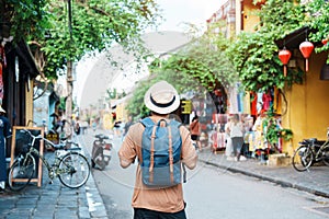 Happy Solo traveler sightseeing at Hoi An ancient town in central Vietnam, man traveling with backpack and hat. landmark and