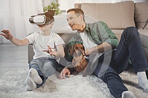 Happy son and dad entertaining with modern device at home