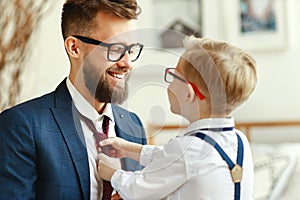 Happy son helps father tie a necktie at home