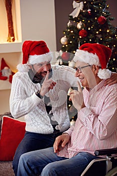 Happy son and his elderly father confessing a secret to each another on Christmas.