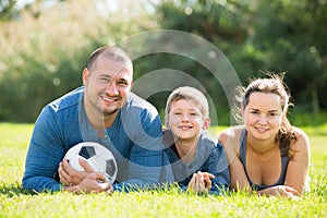 Happy son and parents lying in football field