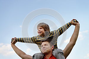 Happy son on the shoulders of the father