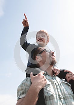 Happy son sits on his father`s shoulders