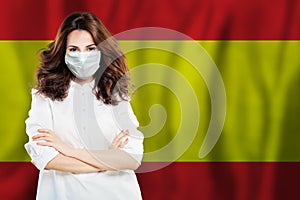 Happy Spanish doctor or nurse in medical safety face mask on Spainish flag background. Flu epidemic and virus protection in Spain