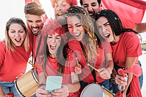 Happy sport supporters watching football on mobile phone - Focus on faces photo