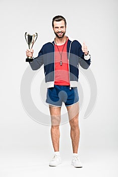 happy sportive coach with trophy cup showing thumb up,