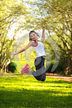 Happy sportive girl jumping in green summer park