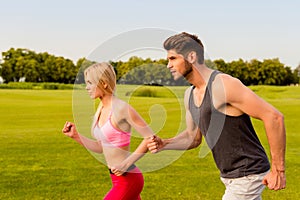 Happy sportive healthy couple in sportswear jogging in the park