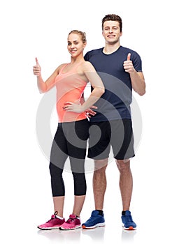 Happy sportive man and woman showing thumbs up