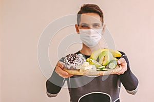 Happy sports man holding healthy and unhealthy food on wooden board