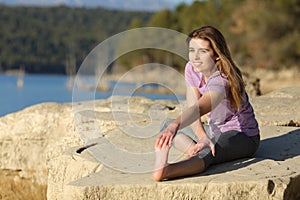 Happy sportswoman stretching leg in nature