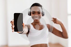 Happy sporty black woman showing phone with blank screen