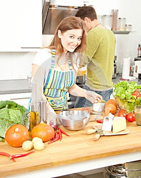 Happy sporty couple is preparing healthy food on light kitchen