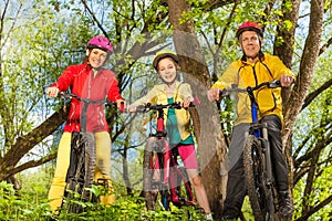 Happy sporty family on the bikes in sunny forest