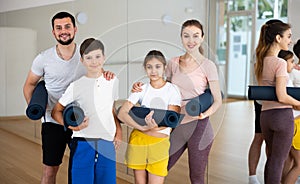 Happy sporty family posing in gym with yoga mats