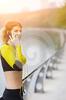 Happy sporty girl talking on phone in park