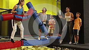 Happy sporty teen girl having fun on battle beam with opponent tween girl over foam pit in indoor amusement park