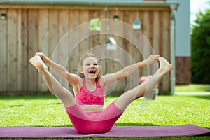 Happy sporty teenage girl practicing pilates on yoga mat at backyard