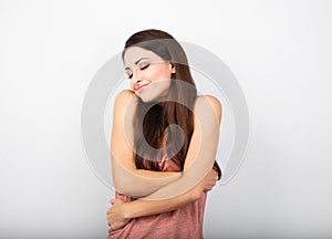 Happy sporty woman hugging herself with natural emotional enjoying face on blue background. Love concept