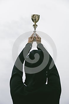 Happy sporty young woman holding gold trophy cup