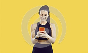 Happy sporty young woman using smartwatch and fitness workout app on her mobile phone
