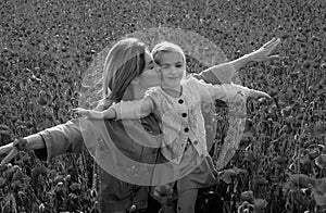 Happy spring family. Carefree mom with a child girl in a field of red poppies enjoys nature. Mother and little daughter