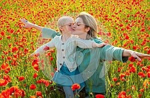 Happy spring family. Mother with daughter on the poppies meadow. Beautiful mom and daughter on a poppy field outdoor