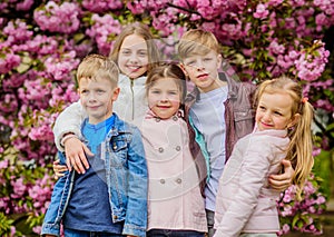 Happy spring vacation. Children enjoy warm spring. Lost in blossom. Girls and boys friends posing near sakura. Kids on