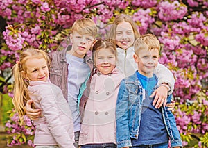 Happy spring vacation. Children enjoy warm spring. Lost in blossom. Girls and boys friends posing near sakura. Kids on