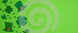 Happy St. Patrick`s Day banner design. Top view shamrock leaf clovers and Irish elf hats on green background. Saint Patricks Day