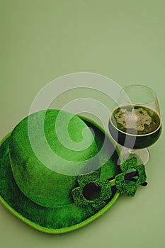 Happy St Patrick`s Day concept. Glass of green beer and party glasses in green background. Greeting card. Top view.