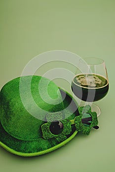 Happy St Patrick`s Day concept. Glass of green beer and party hat in green background. Greeting card. Top view.