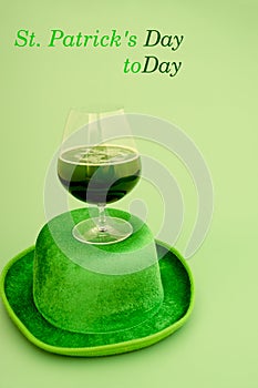 Happy St Patrick`s Day concept. Glass of green beer and party hat in green background. Greeting card. Top view.