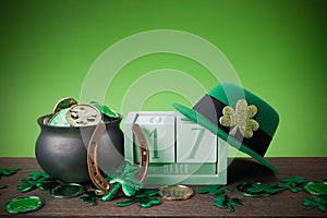 Happy St. Patrick's day. Shiny shamrocks, gold coins and leprechaun hat on a wooden background