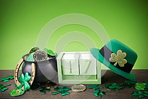 Happy St. Patrick's day. Shiny shamrocks, gold coins and leprechaun hat on a wooden background