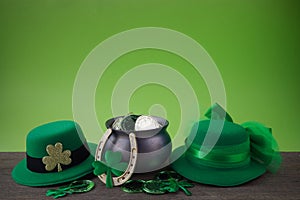 Happy St. Patrick's day. Shiny shamrocks, gold coins and leprechaun hat on a wooden background