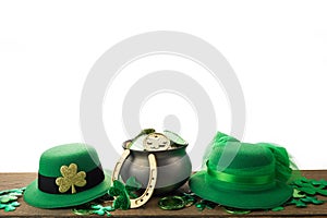 Happy St. Patrick's day. Shiny shamrocks, gold coins and leprechaun hat on wooden table isolated on white backgorund.
