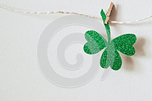 Happy St. Patricks day. Green glitter shamrocks decoration. Shiny paper cut clover leaf on clothespin
