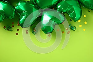 Happy St Patricks Day greeting card design. Green shamrock shaped balloons with confetti on light green background. Flat lay, top