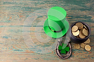 Happy St Patricks Day leprechaun hat with gold coins and lucky charms on vintage style green wood background. Top view