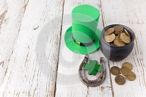 Happy St Patricks Day leprechaun hat with gold coins and lucky charms on vintage style white wood background. Top view