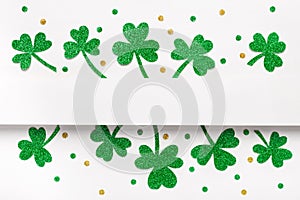 Happy St. Patricks Day minimal background. Green glitter shamrocks border on white background