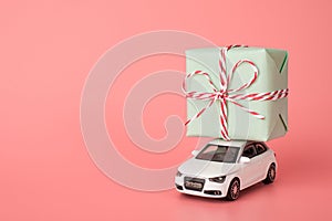 Happy st Valentines day shopping time concept. Photo of small mini modern car holding huge wide gift on top roof isolated light